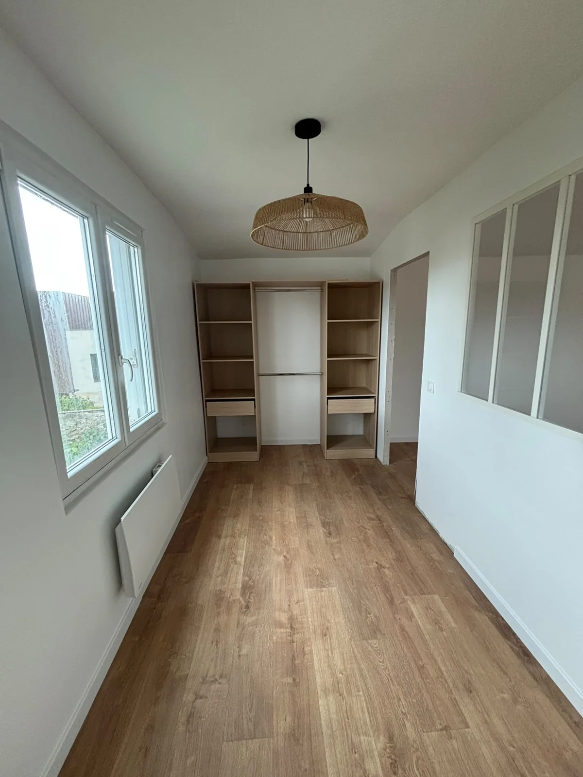 Une pièce rénovée avec sol d’aspect bois et modules de rangement.